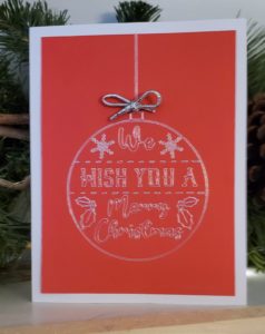 a red christmas card made with a cricut cutting machine with a foil transfer application of a christmas ornament on the front in silver foil