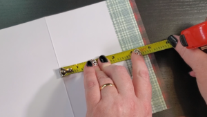 a woman's hands measuring the top of a christmas card 